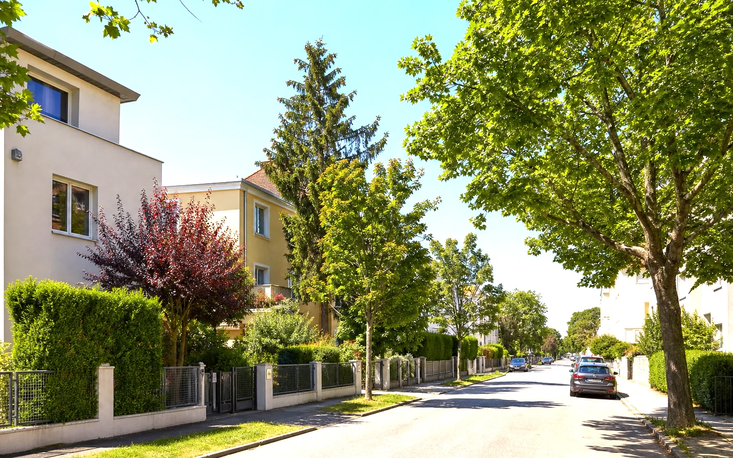 Begrünte Wohnstraße mit Mehrfamilienhäusern – KI-Symbolbild